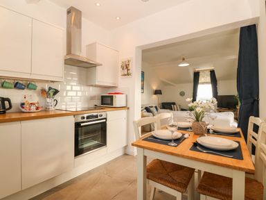 A kitchen with appliances and dining area at Llywelyn Trearddur Bay