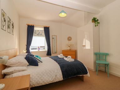 A bedroom with a bed, dresser and mirror at Llywelyn Trearddur Bay