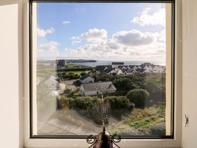 A view from a window showing houses and the sea at Llywelyn in Trearddur Bay