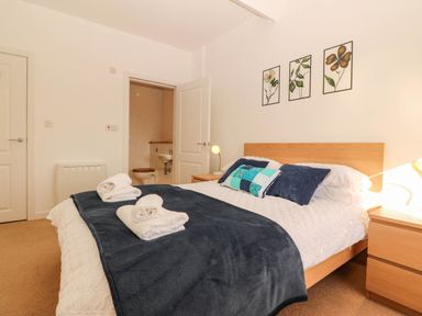 A bedroom with a bed and bathroom access at Llywelyn in Trearddur Bay