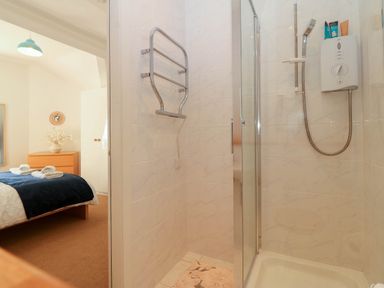 A bathroom with a shower and a bed at Llywelyn in Trearddur Bay