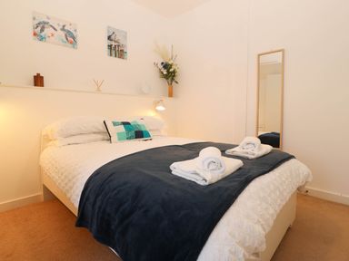 A bedroom with a bed and towels arranged at Llywelyn in Trearddur Bay