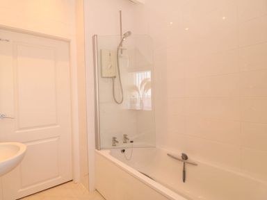 A bathtub with shower in a bathroom at Llywelyn in Trearddur Bay