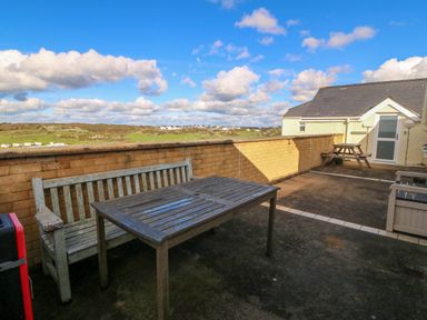 An outdoor space with a table and benches at Llywelyn in Trearddur Bay