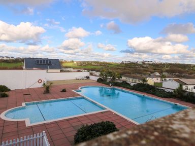 An outdoor swimming pool area with sunloungers at Llywelyn Trearddur Bay