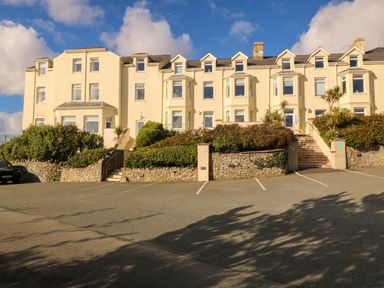 A building with multiple windows and landscaping at Llywelyn in Trearddur Bay