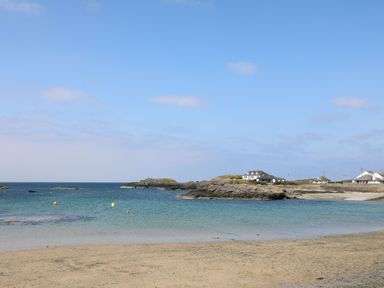 A beach scene with houses and water at Llywelyn in Trearddur Bay