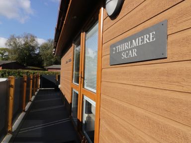 A wooden exterior with a sign and decking at Thirlmere Scar in Troutbeck Bridge