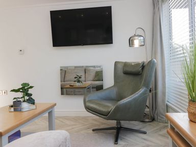A living room with a chair and a television at Thirlmere Scar in Troutbeck Bridge