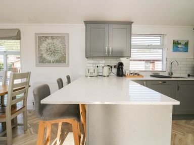 A kitchen with cabinets, island, sink, and dining table at Thirlmere Scar in Troutbeck Bridge