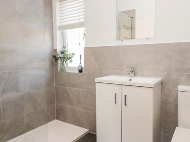 A bathroom with a shower, basin, and toilet at Thirlmere Scar in Troutbeck Bridge