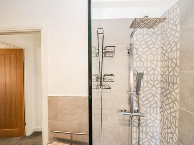 A bathroom with a shower and storage racks at Thirlmere Scar in Troutbeck Bridge