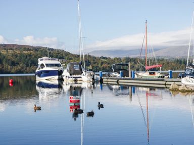 Boats moored at a pier with ducks in the water at Thirlmere Scar Troutbeck Bridge