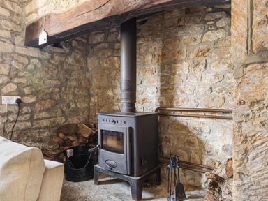 A living room with a wood-burning stove and stone walls at The Old Barn in Manchester