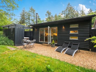 An outdoor seating area with chairs and table at a cabin in the woods
