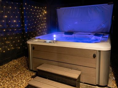 A hot tub with steps and decorative lights in an outdoor area