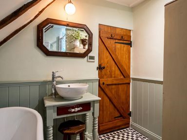 A bathroom with a sink, mirror, and bathtub at The Old Barn in Manchester