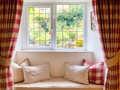 A sitting room with a window and cushions at The Old Barn in Manchester