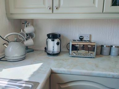 A kitchen countertop with a kettle, coffee machine, toaster, and canisters at a property