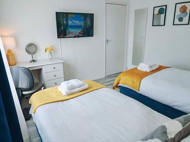 A bedroom with two beds, a desk, and a television at the property in the location
