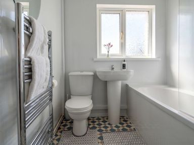 A bathroom with a toilet, sink, bathtub, and towel rack at The Old Barn in Manchester
