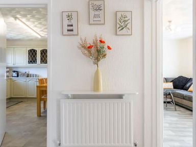A hallway with a vase on a shelf and access to a kitchen and living room at The Old Barn in Manchester