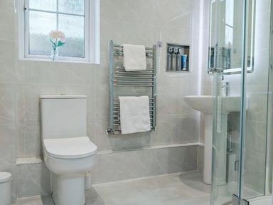 A bathroom with a toilet, sink, shower and towel rail at 