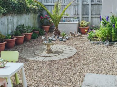 A garden with a birdbath and flower pots at a residential property