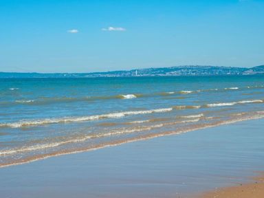 A beach with waves and clear sky at the shore