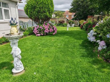A garden with flowers and a stone statue at The Old Barn in Manchester
