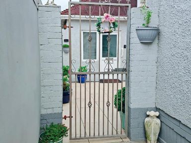 A garden gate with plants and a house in the background at the property