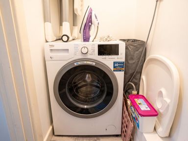 A washing machine with an iron and laundry basket in a laundry room at 
