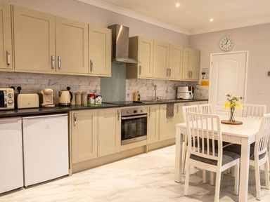 A kitchen with cabinets, appliances, and a dining table at The Old Barn in Manchester