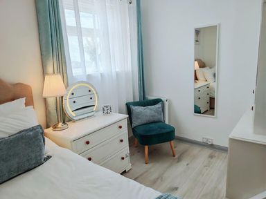 A bedroom with a bed, chair, mirror, and chest of drawers at the property in the location 