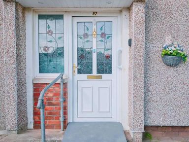 A front door with stained glass and a flower basket at an entrance
