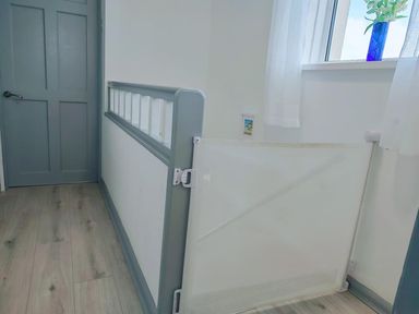 A hallway with a door and a safety gate at a property