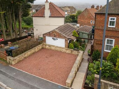 An outdoor view of a house and garage with a garden area at a residential property