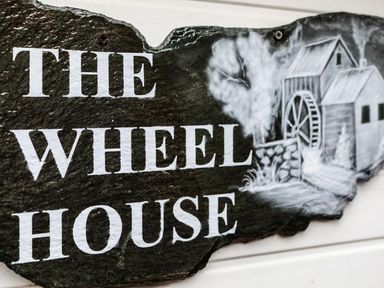A stone sign with the text The Wheel House and an illustration of a watermill