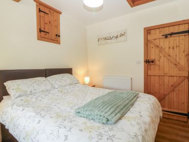 A bedroom with a bed and wooden door at Bryn Eithin in Penygroes