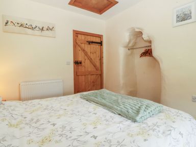 A bedroom with a bed and a wooden door at Bryn Eithin in Penygroes