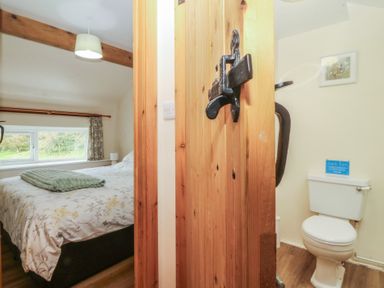 A bedroom with a bed and a door leading to a bathroom at Bryn Eithin Penygroes