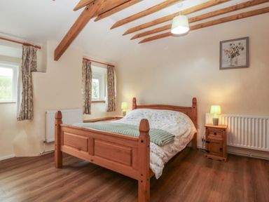 A bedroom with a bed, bedside table, and windows at Bryn Eithin in Penygroes