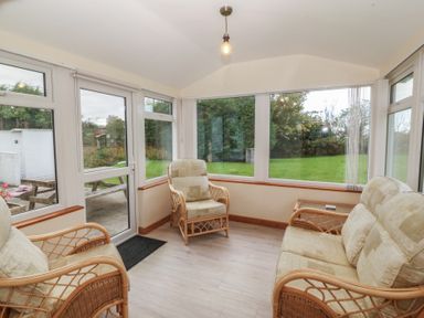 A conservatory with seating and windows at Bryn Eithin in Penygroes
