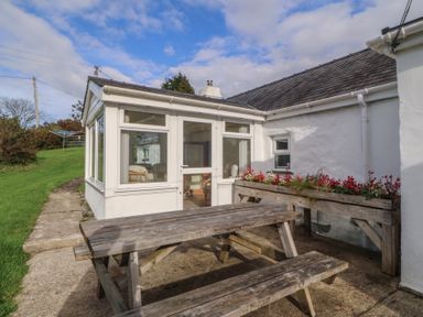 An outdoor patio with a wooden table and benches at Bryn Eithin in Penygroes