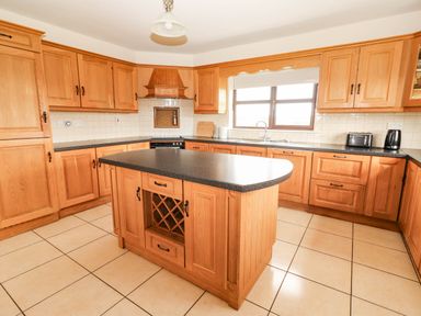 A kitchen with wooden cabinets and an island at Wild Atlantic Ferry View, Kilrush, County Clare
