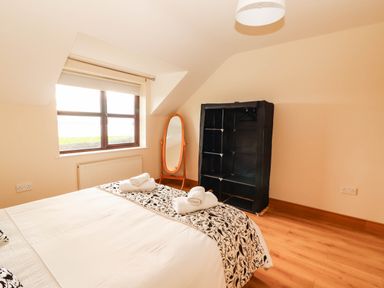 A bedroom with a bed and a wardrobe at Wild Atlantic Ferry View, Kilrush, County Clare