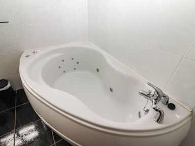 A bathtub with a faucet and wall tiles at Wild Atlantic Ferry View in Kilrush, County Clare