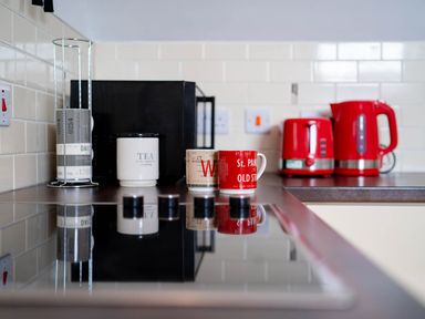 A kitchen with mugs, kettle, and microwave at Limavady Cherry Tree Apartment, Sleeps 2 and Parking, Limavady