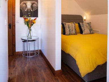 A bedroom with a yellow bedspread and a vase of flowers at Limavady Cherry Tree Apartment, Sleeps 2 and Parking Limavady