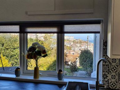 A kitchen with a window view and flowers in a vase at 1 Bedroom Apartment with Sea View, Mevagissey